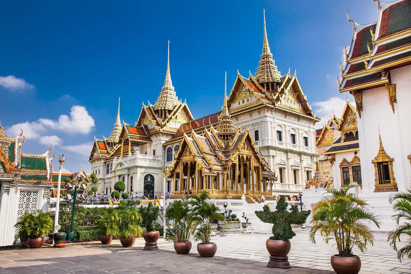The Grand Palace in Bangkok, Thailand, with its ornate golden spires and traditional Thai architecture, set against a bright blue sky.