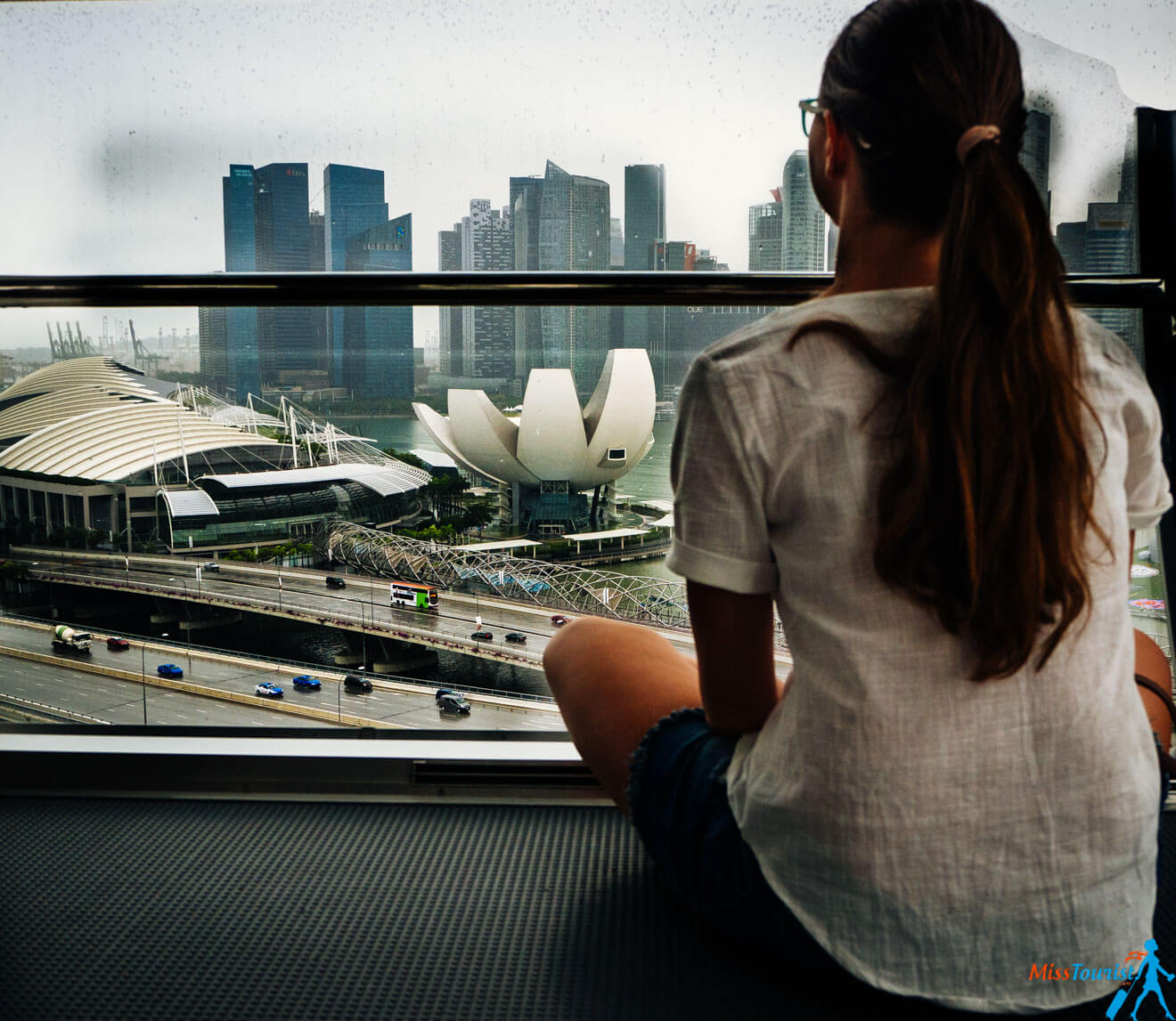 A woman looking out a window towards Singapore skyline