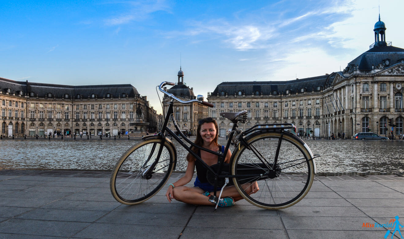 The author of the post is posing with a bicycle in front of the Bordeaux Place de la Bourse's Miroir d'Eau.
