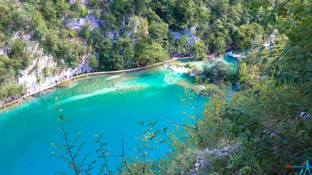 Aerial view of a curved boardwalk spanning across the stunning turquoise waters of Plitvice Lakes
