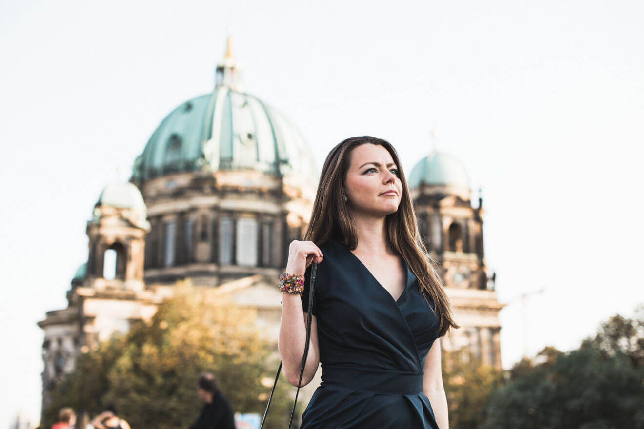 A woman in a black dress standing in front of a building.