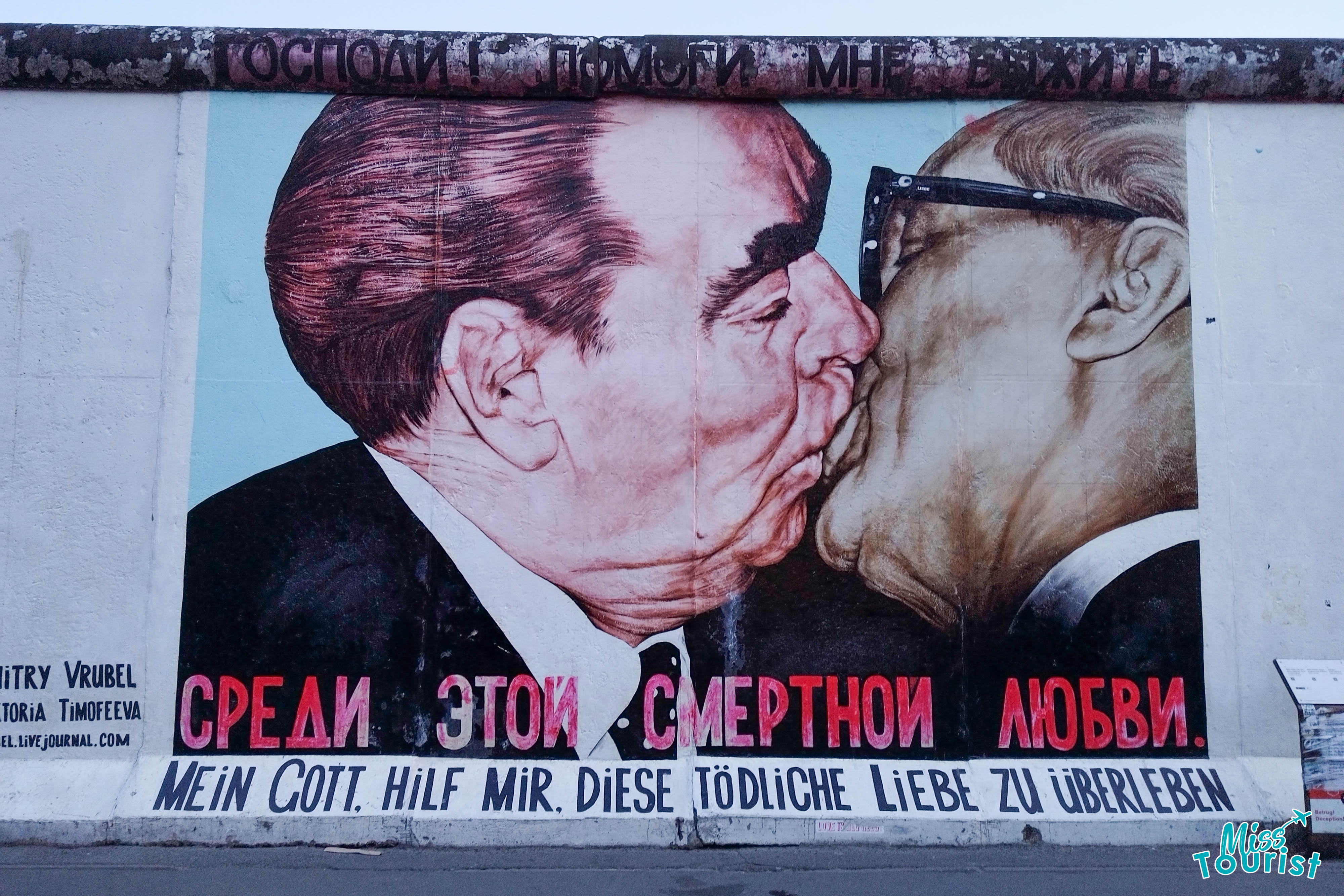 Mural depicting two men sharing a kiss, with text in various languages.