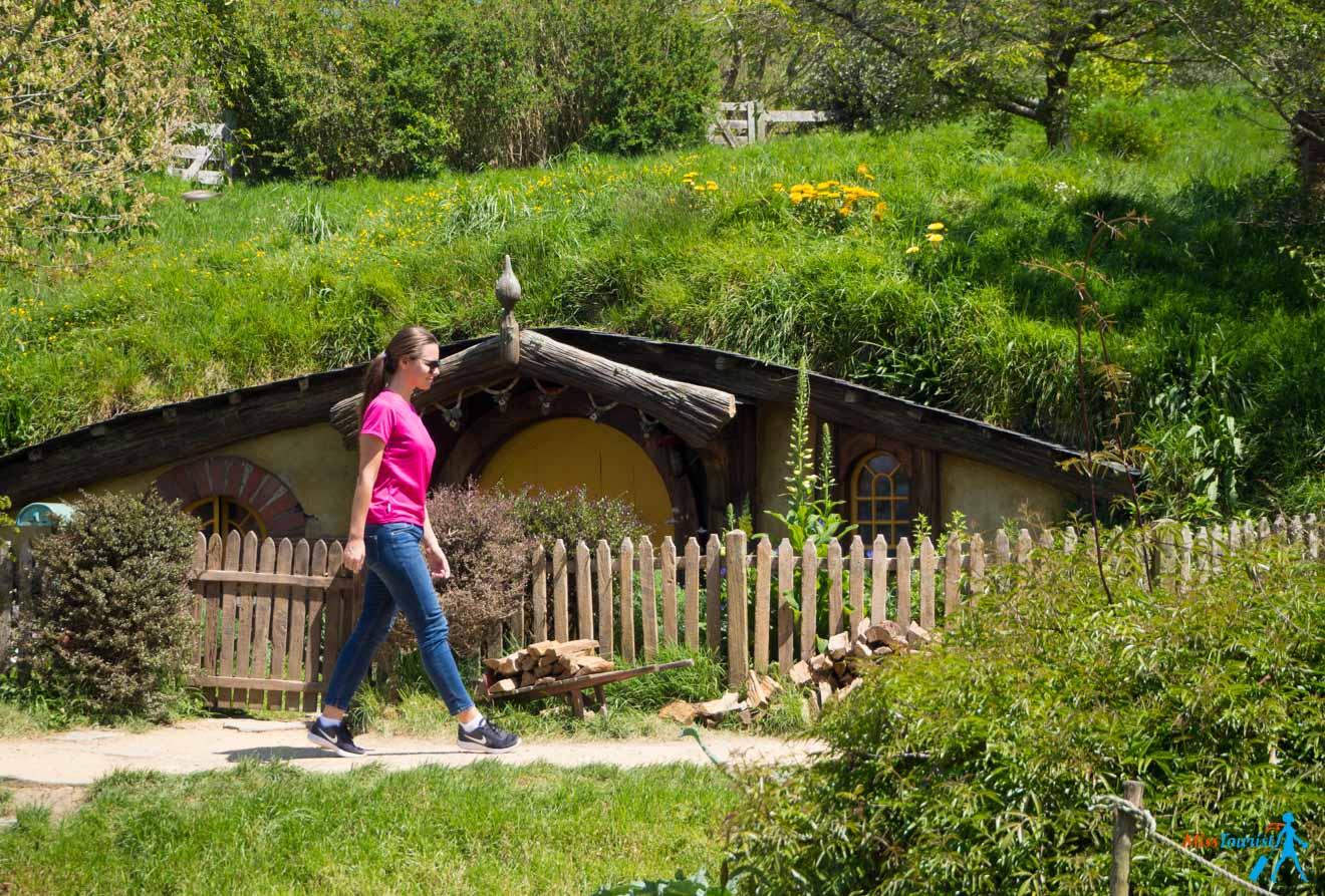 a woman walking past a hobbit house in the woods