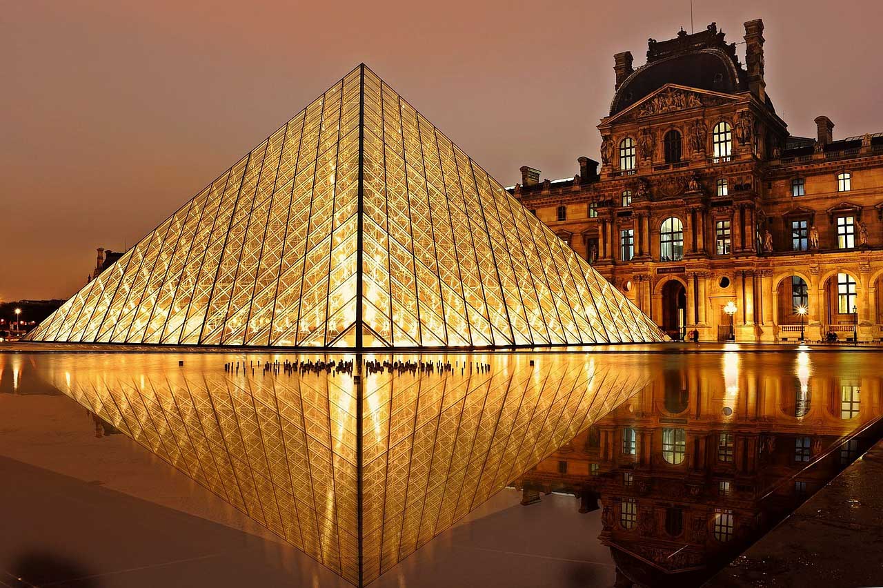 The pyramid of the louvre is lit up at night.