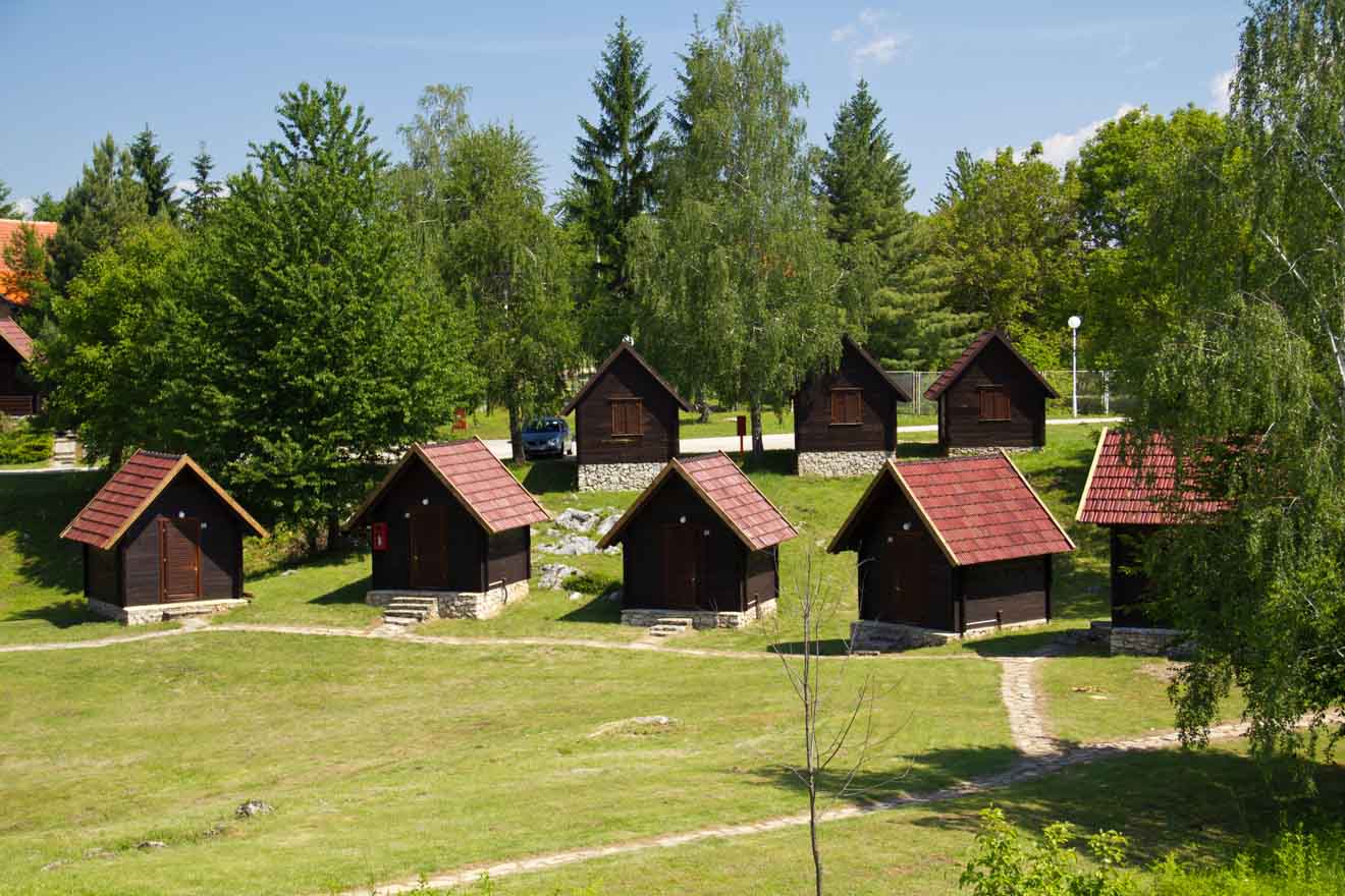 Row of wooden bungalows with red roofs in a lush green setting at Plitvice Lakes