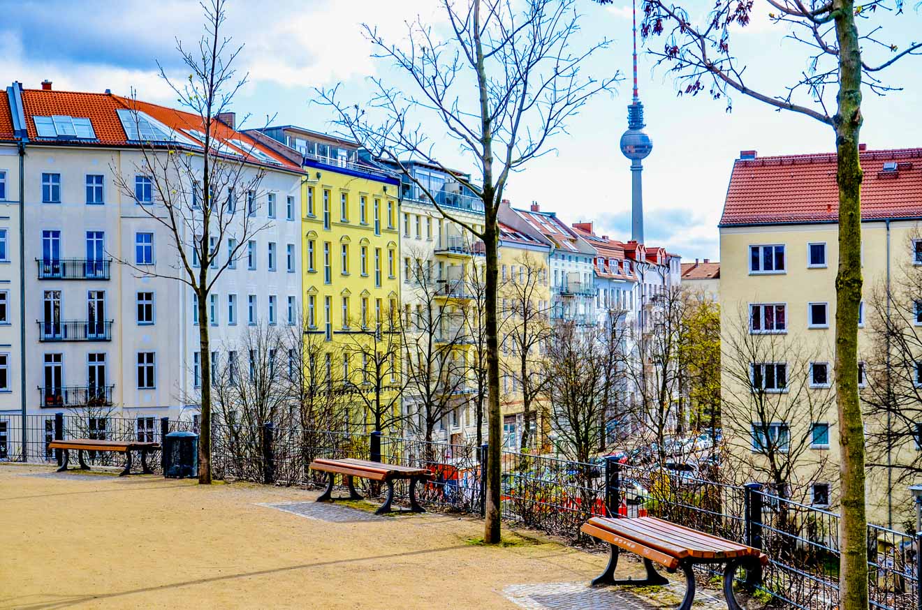 a park with benches and trees in front of buildings