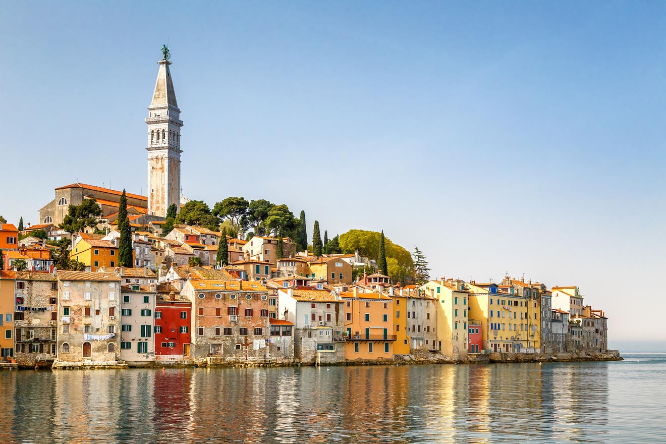 The iconic bell tower of Rovinj rises majestically above terracotta rooftops and colorful buildings, reflecting the charm of this Adriatic seaside town in the golden light of morning