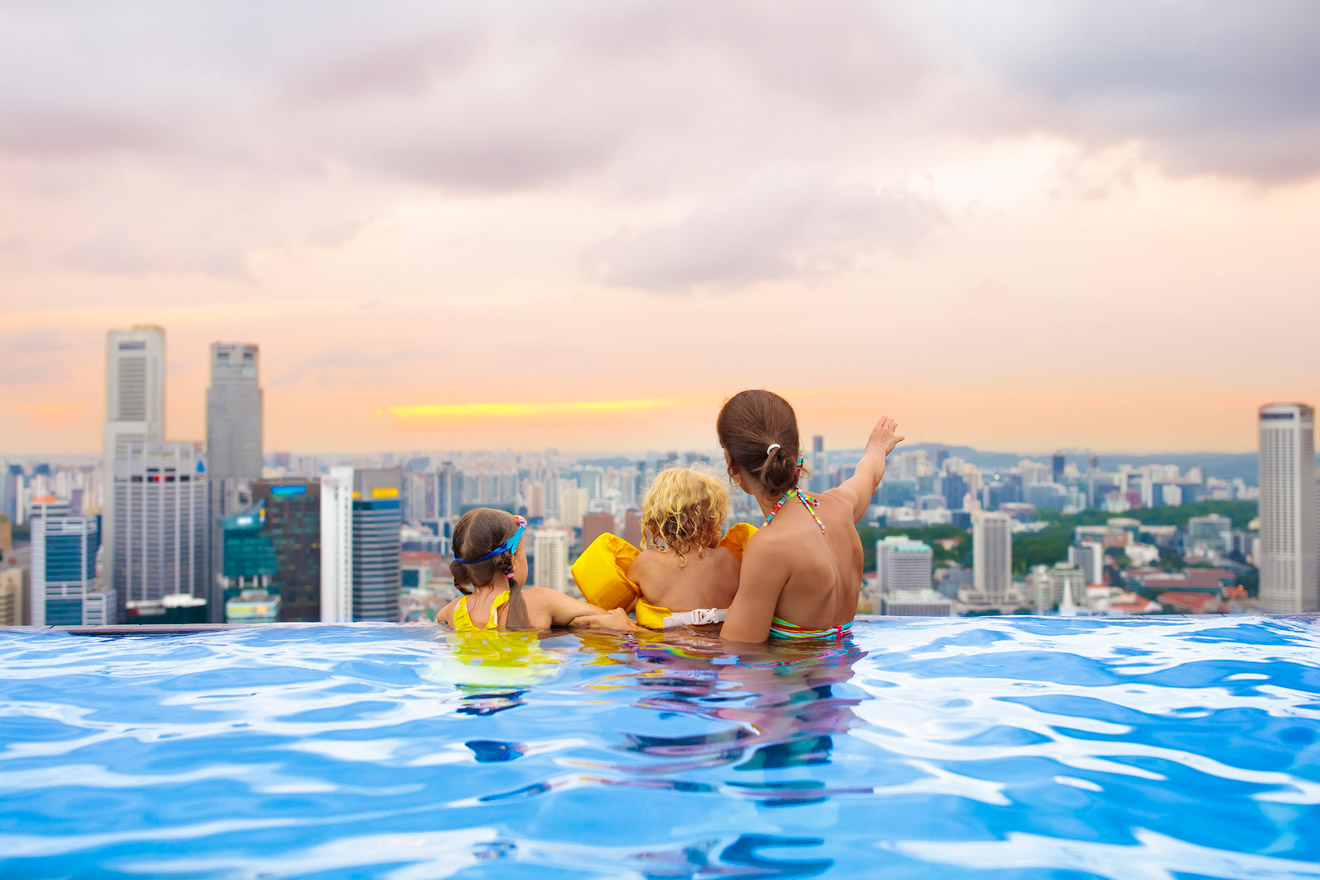 A family in a swimming pool overlooking a city.