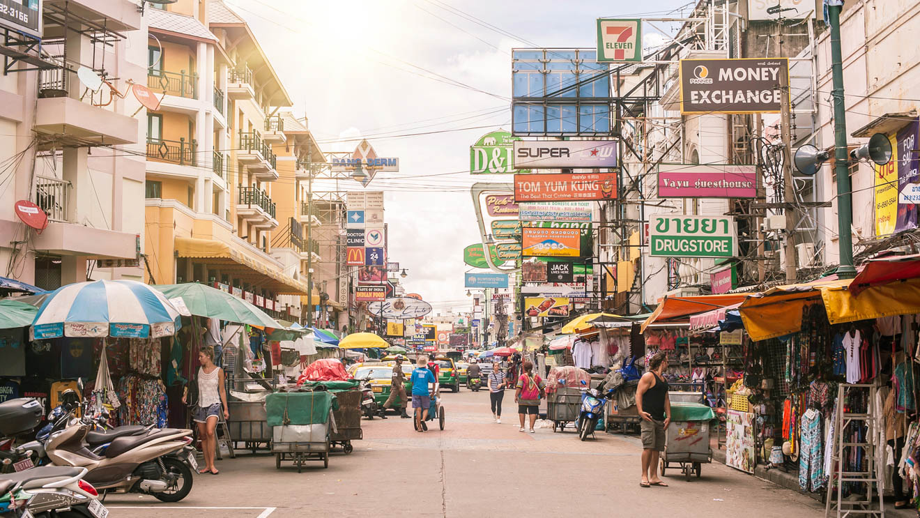 Busy day on Khao San Road in Bangkok, with street vendors, colorful signs, and tourists exploring the local market scene.