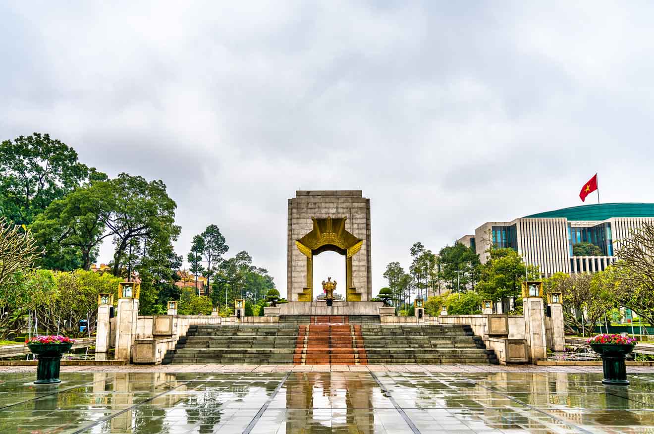 Monument to the Heroic Martyrs in Hanoi, a large sculptural lotus flower on a pedestal, with the National Assembly Building in the background on an overcast day