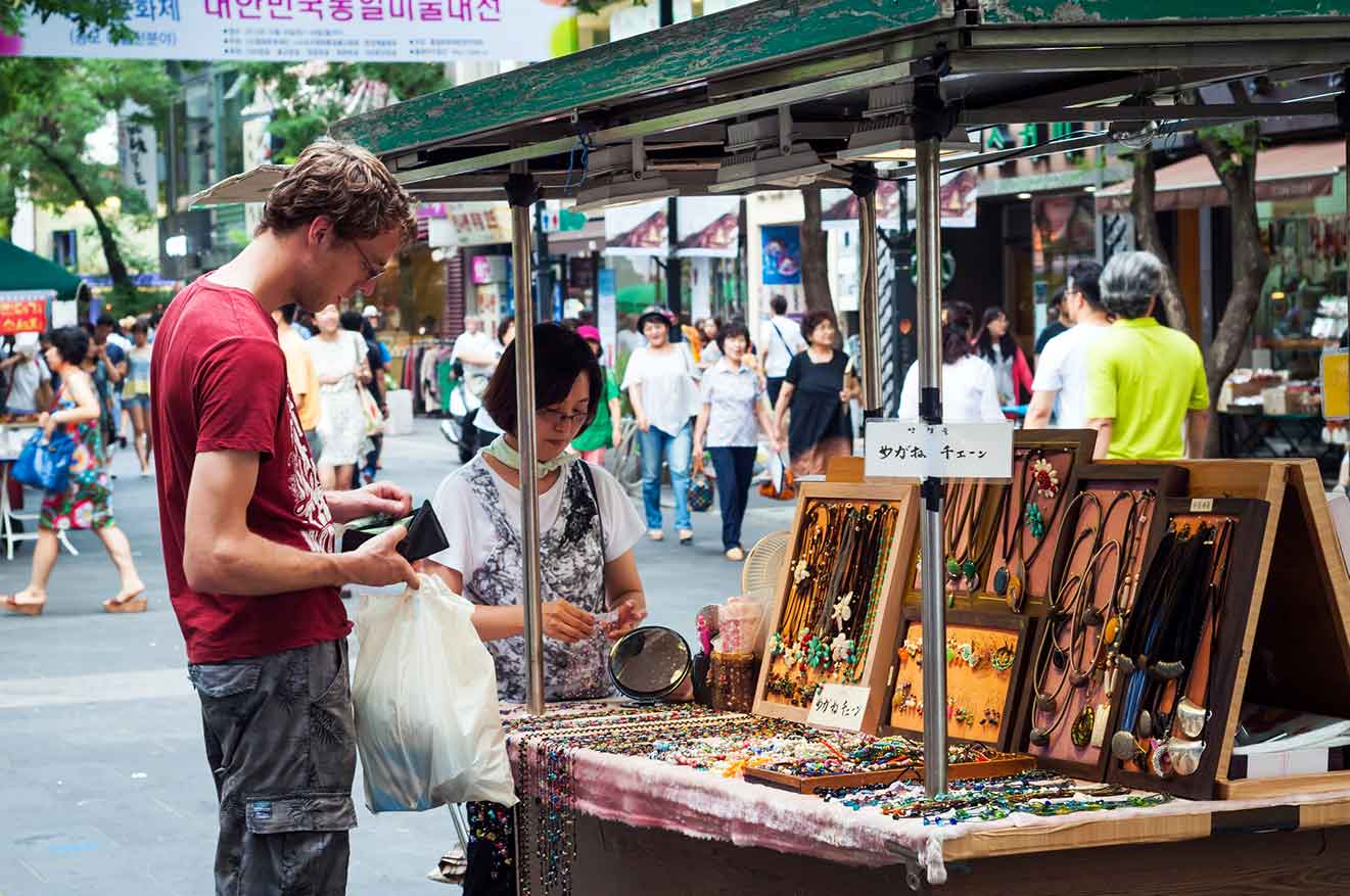 A man looking at jewelry at the Itaewon street market.