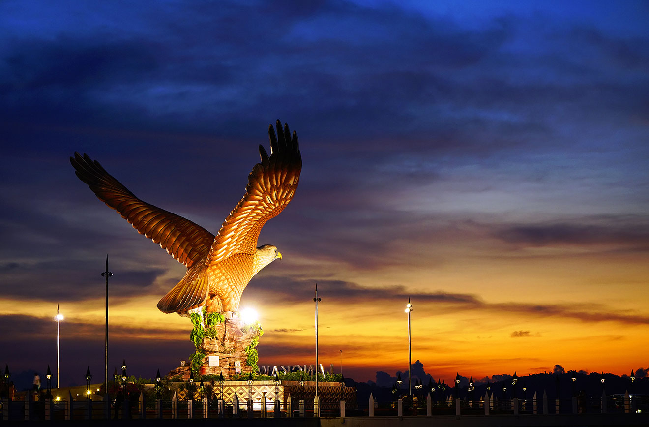 A majestic eagle statue  in Langkawi illuminated at dusk with a sunset backdrop, symbolizing freedom or a landmark.