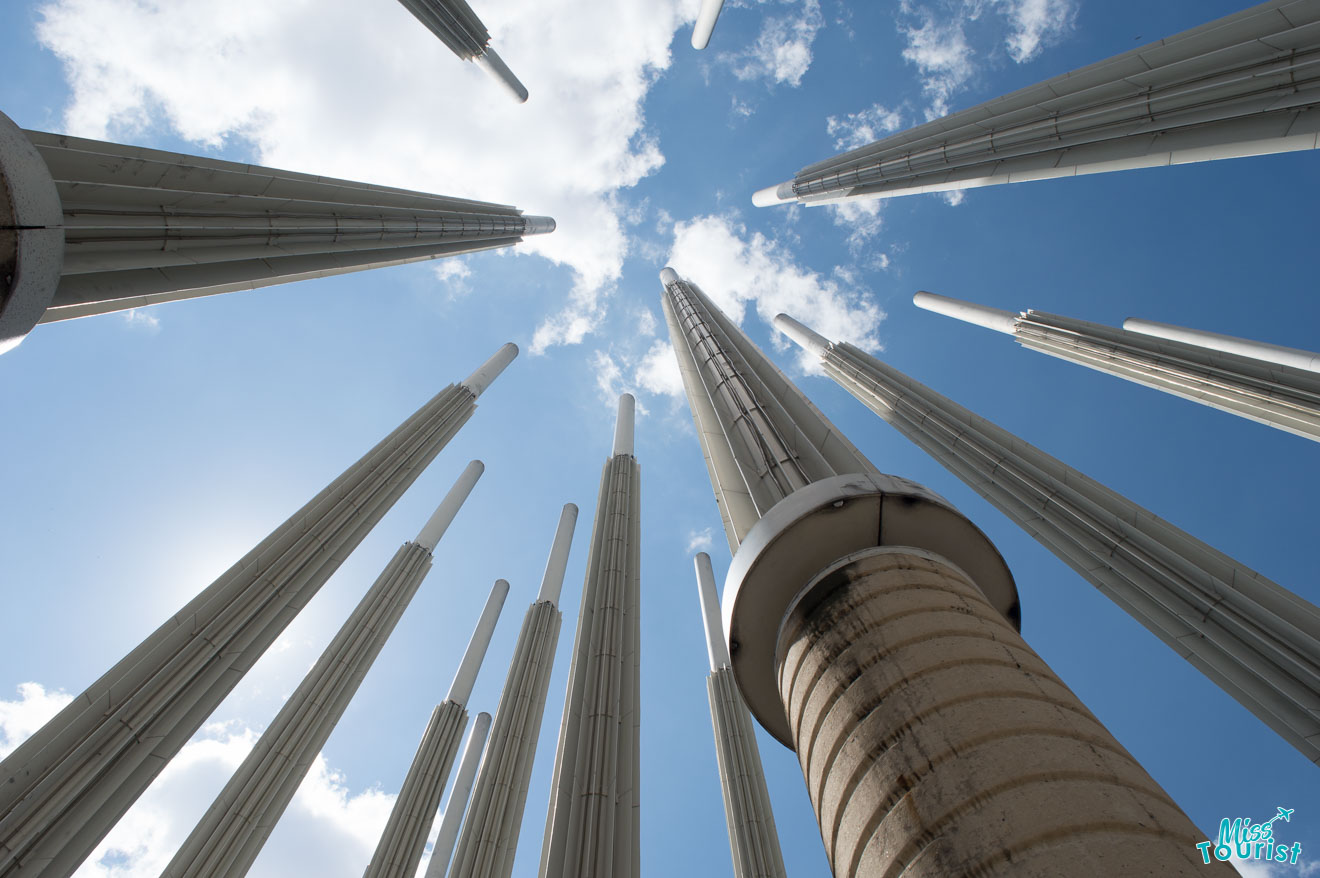 A picture from a low-view of a group of tall metal poles with a blue sky in the background in Medellin