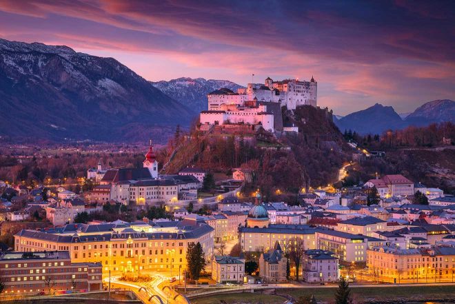 Twilight view of Salzburg with the Hohensalzburg Fortress illuminated against a purple sky