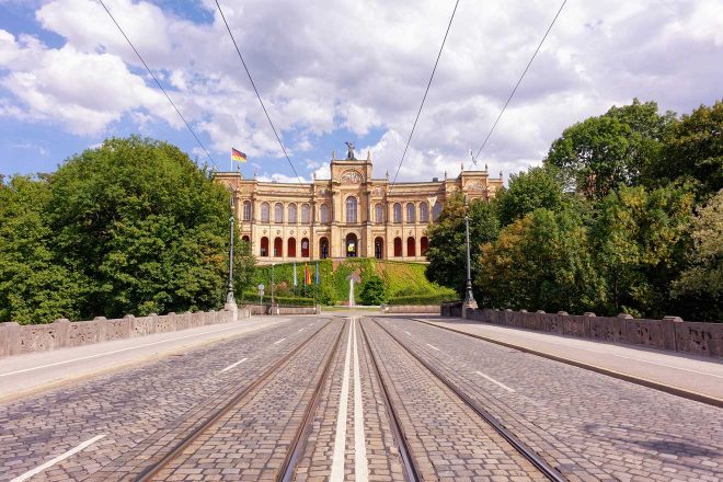 Tram tracks on a street with a large building at the end of it