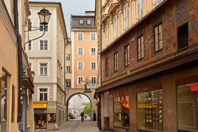 Narrow alley in Salzburg with shops and a traditional archway leading to an open area