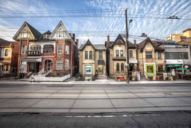 A charming row of Victorian houses in Toronto with distinct architectural details, under a clear blue sky