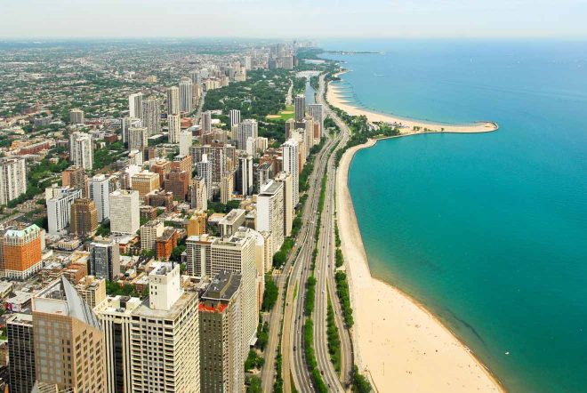 Aerial view of Chicago's coastline showing a sandy beach, clear blue waters, and a dense urban skyline