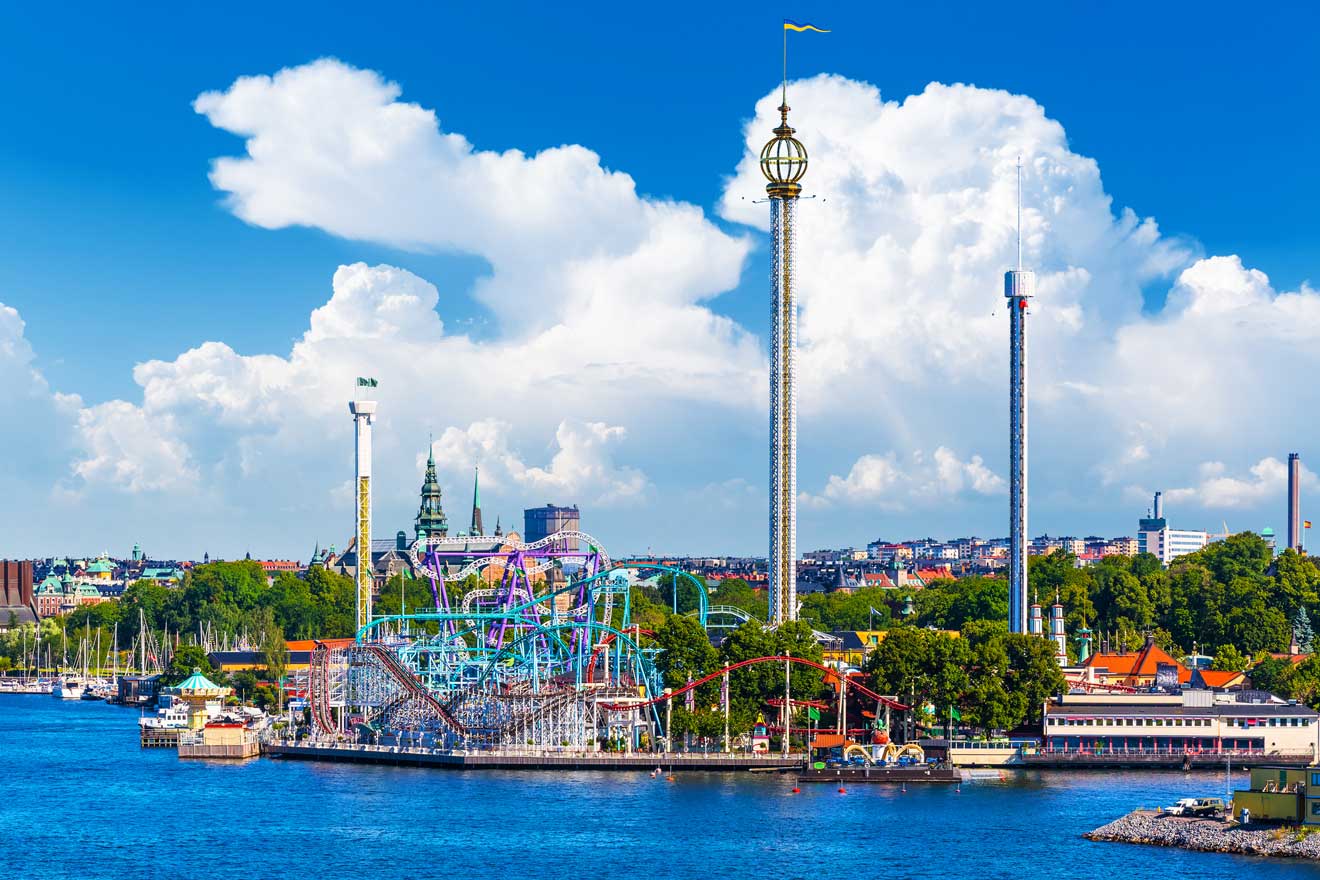 Amusement park rides at Gröna Lund in Stockholm with cityscape and blue sky in the background
