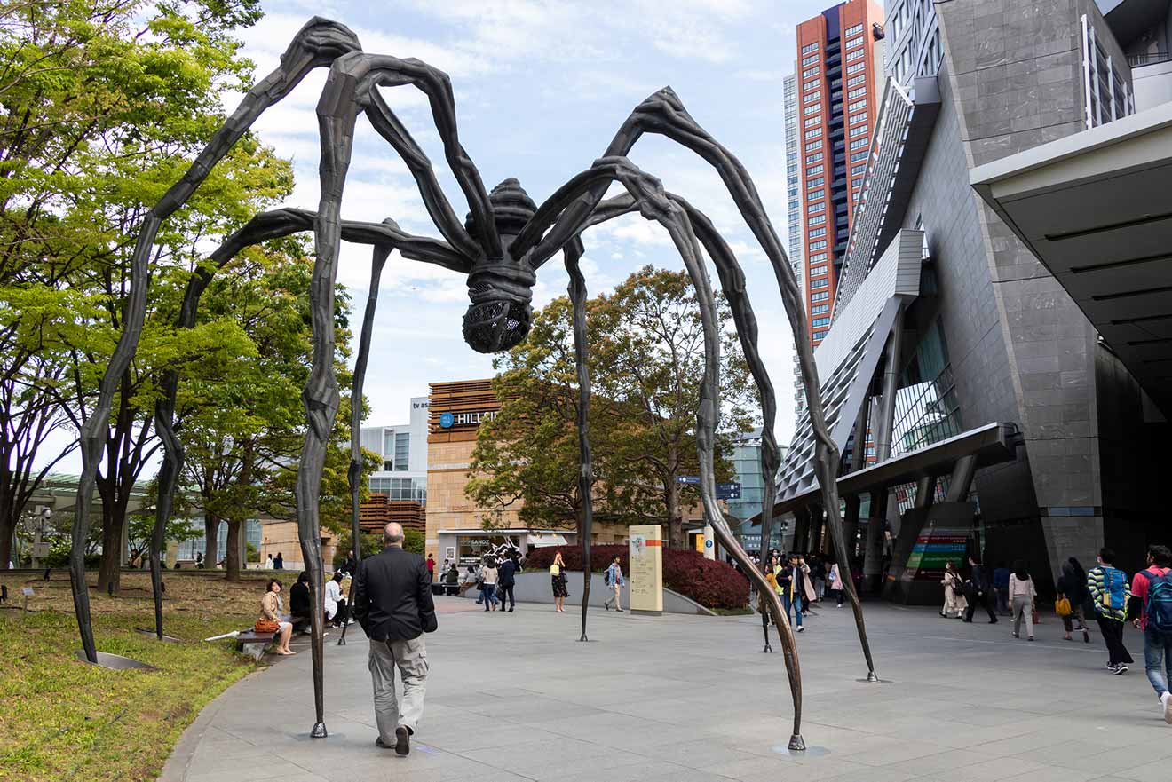The iconic "Maman" spider sculpture by Louise Bourgeois in Roppongi Hills, Tokyo, with people walking around the plaza