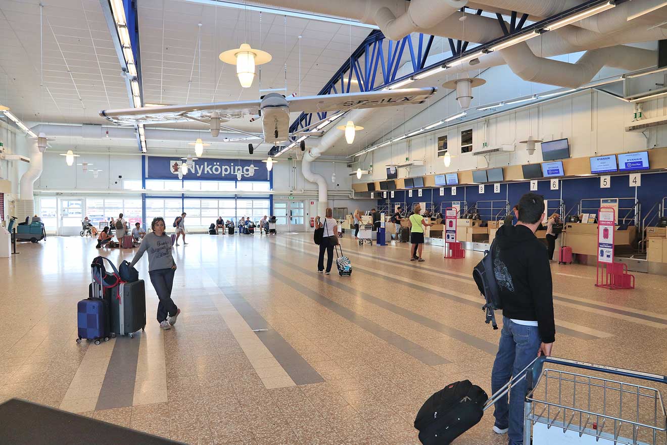 Inside a spacious and modern airport terminal with passengers and signage
