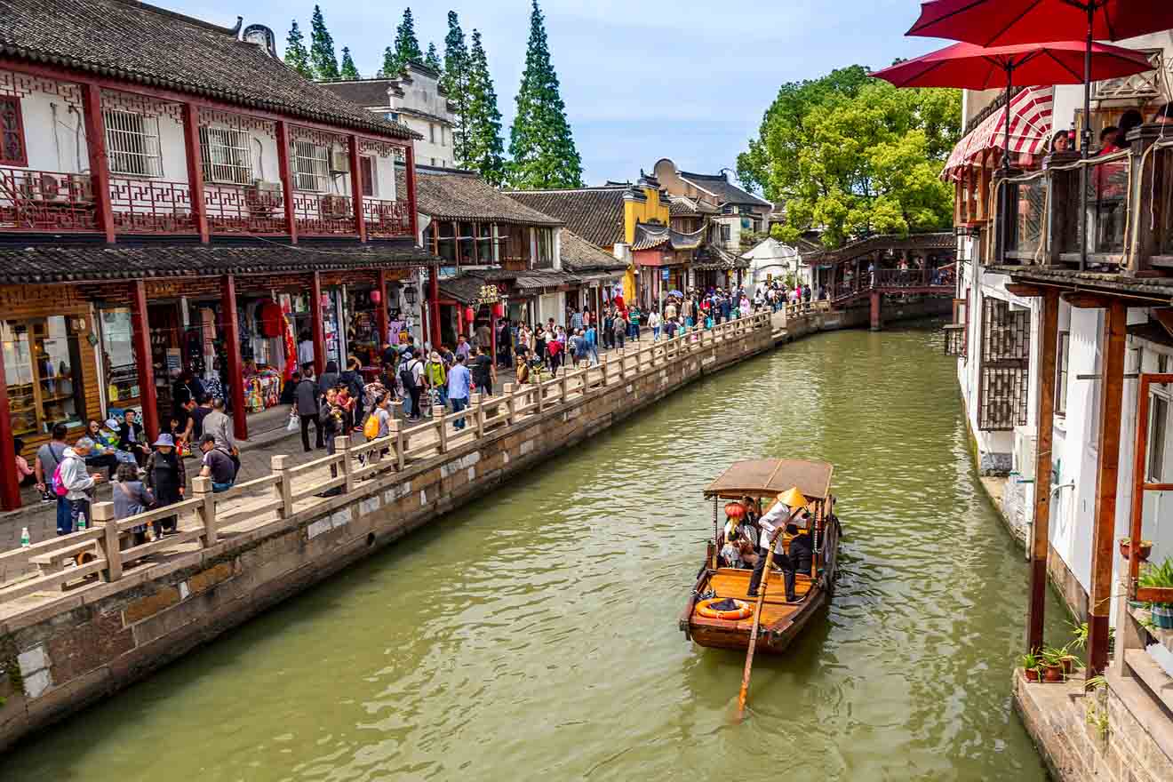 Traditional Chinese architecture along the waterways of Shanghai Old Town, with a boat and tourists in view