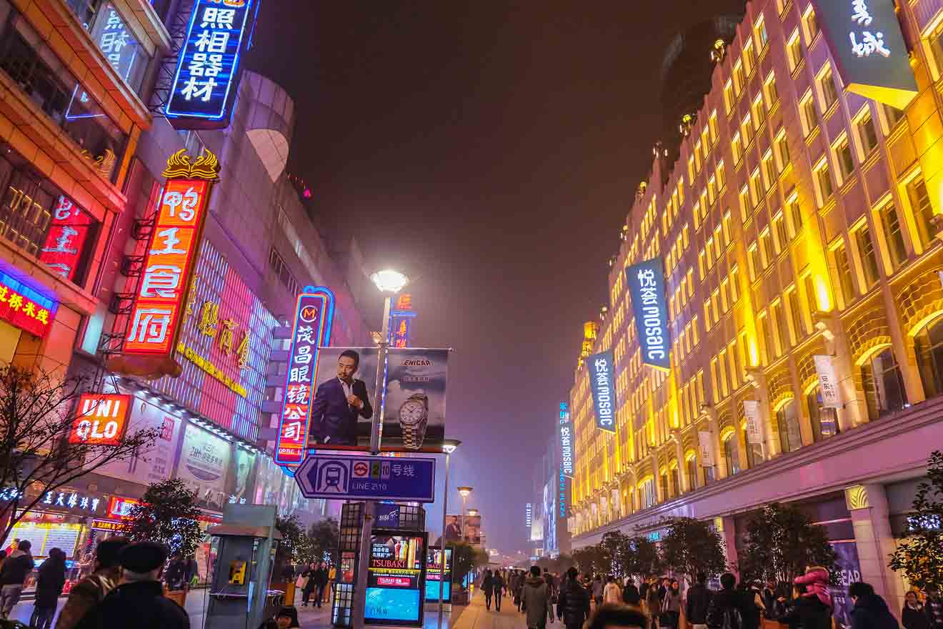 Nanjing Road in Shanghai at night, illuminated by bright neon signs and crowded with shoppers