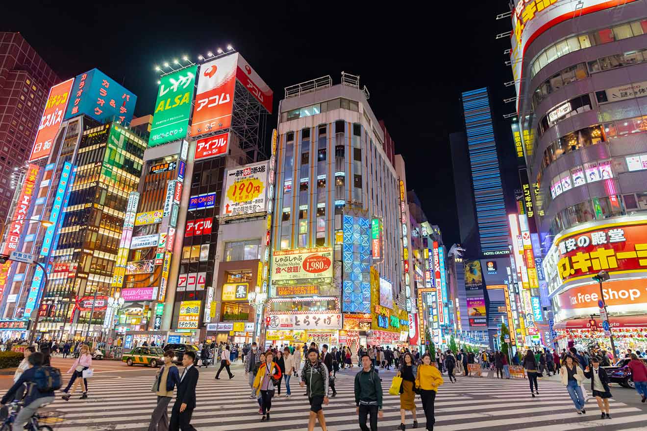 A vibrant Tokyo street at night crowded with pedestrians and adorned with neon signs and colorful billboards