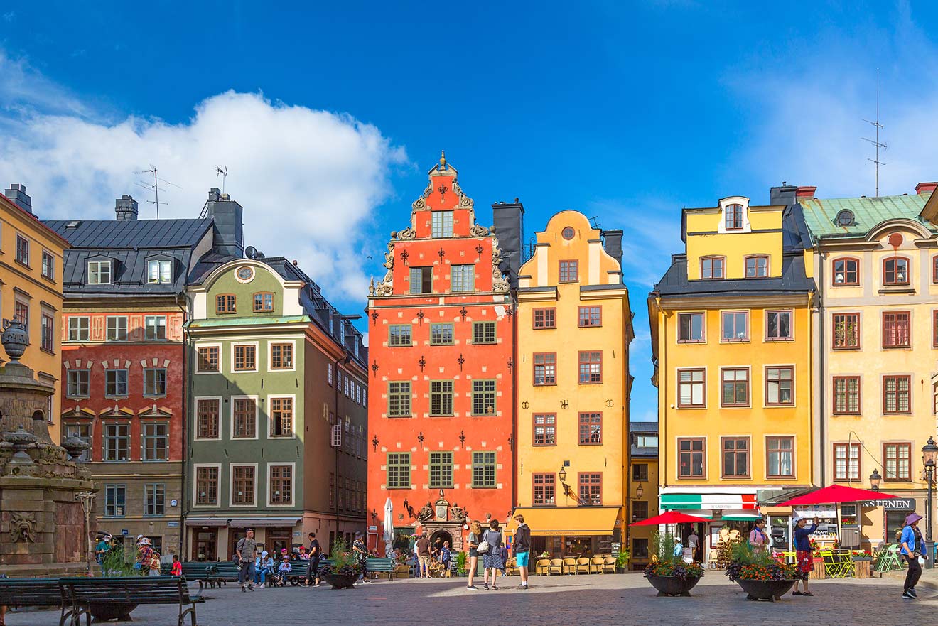 Colorful facades of old town Stockholm buildings in Stortorget square with people milling about
