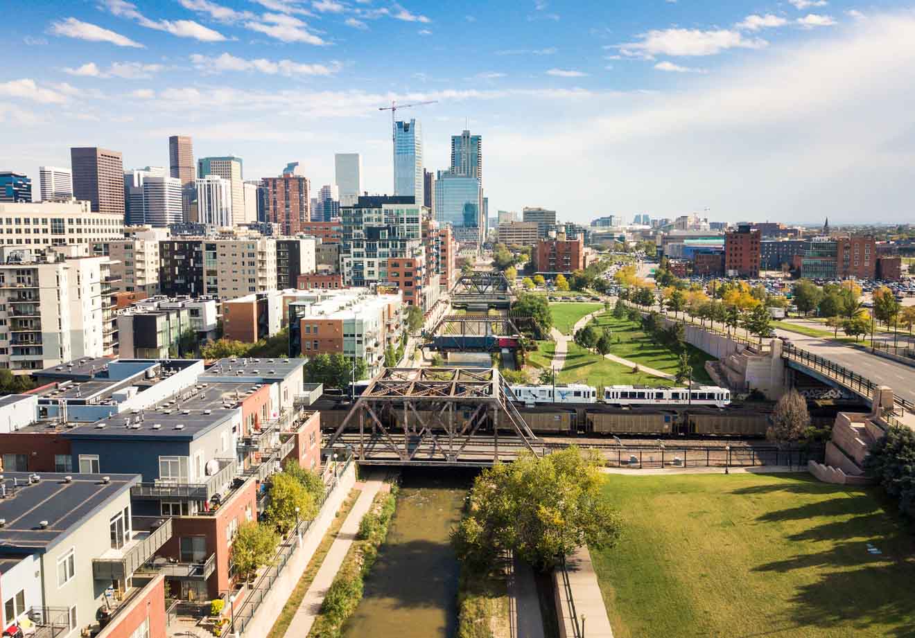 Aerial view of a downtown cityscape with high-rise buildings, green spaces, and a train passing through, highlighting urban development and transportation