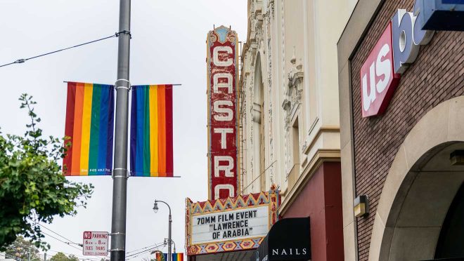 The vibrant marquee of the Castro Theatre in San Francisco, announcing a 70mm film event, with pride flags waving under an overcast sky,