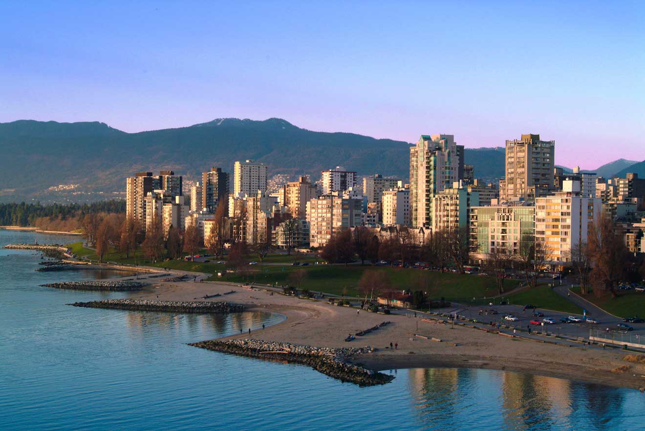 Scenic sunset over Vancouver's beachfront with mountains in the background and a calm bay in the foreground.