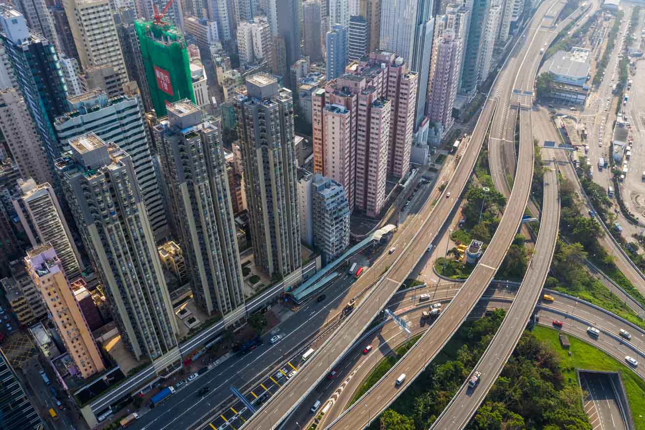 An aerial view showcasing Hong Kong's infrastructure, with high-rise buildings alongside complex roadways and traffic movement.