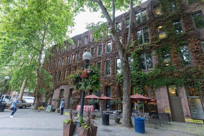 harming street view of a brick building covered in ivy with outdoor seating in Seattle, showcasing the city's urban greenery