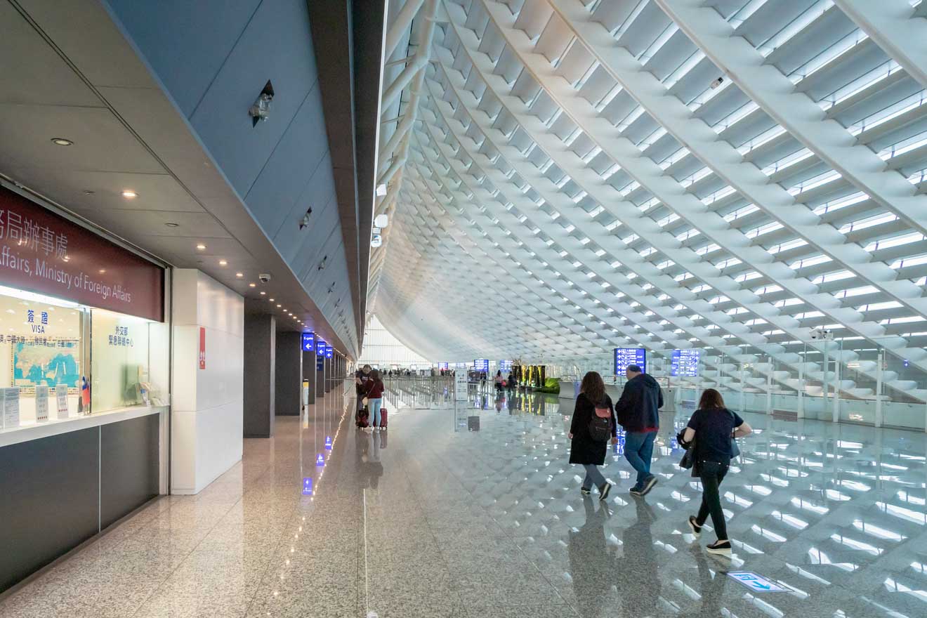 Interior of a modern airport building in Taipei featuring a futuristic white geometric ceiling with people walking below