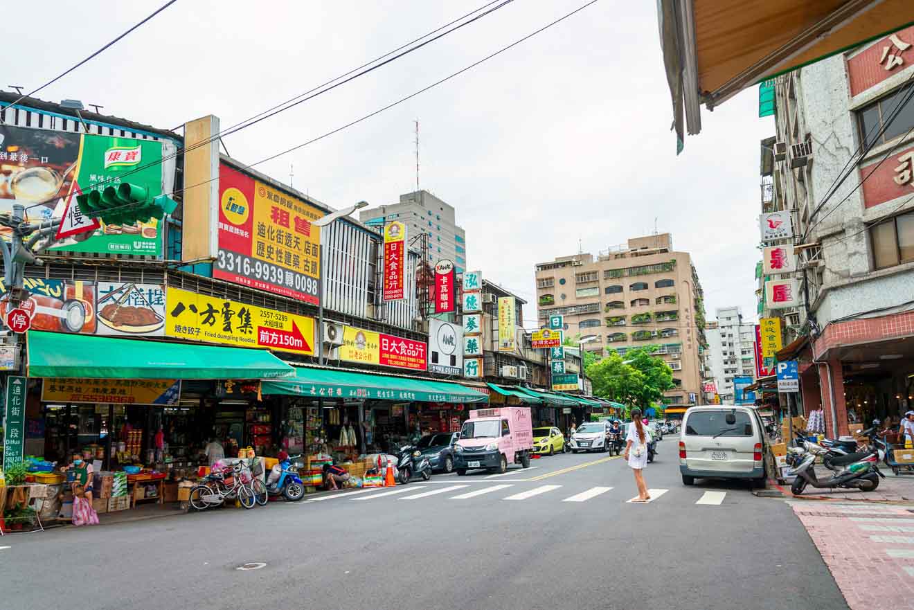 Street view of a traditional market in Taipei with signs and shoppers in daylight
