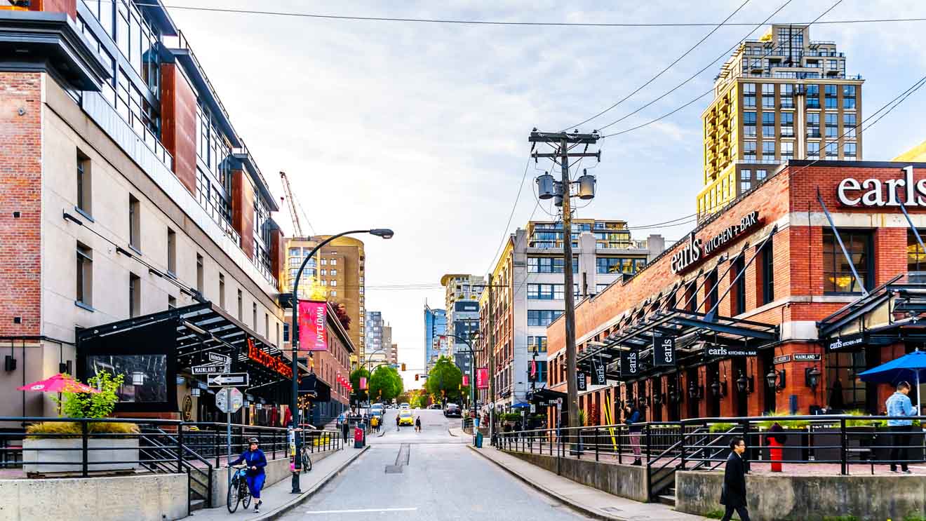 Urban scene of a vibrant street in Vancouver with contemporary buildings and Earls Kitchen + Bar restaurant.