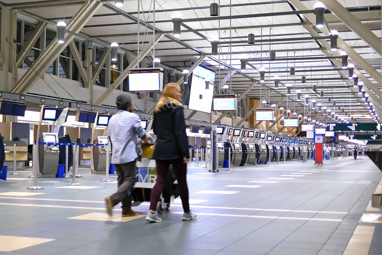 Interior of a quiet Vancouver airport terminal with self-service kiosks and few passengers.