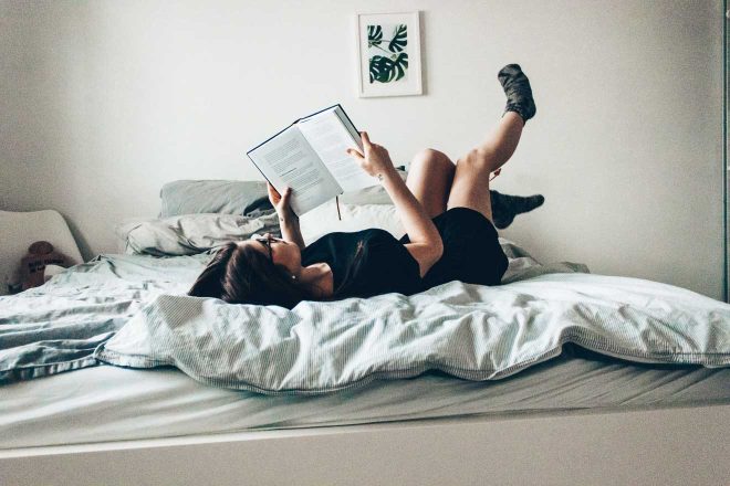 woman laying on bed reading