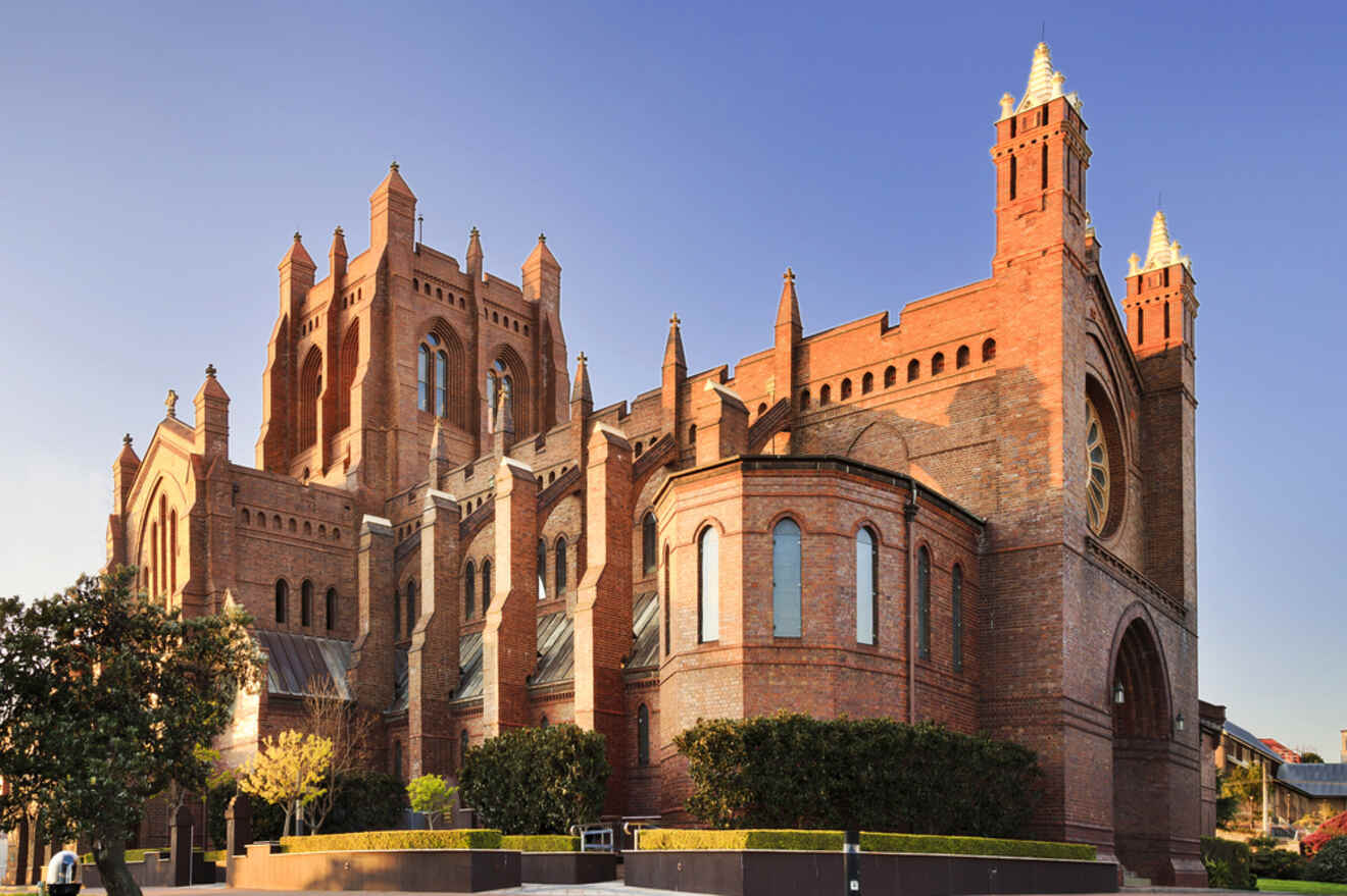 A large brick church with pointed towers against a clear blue sky.