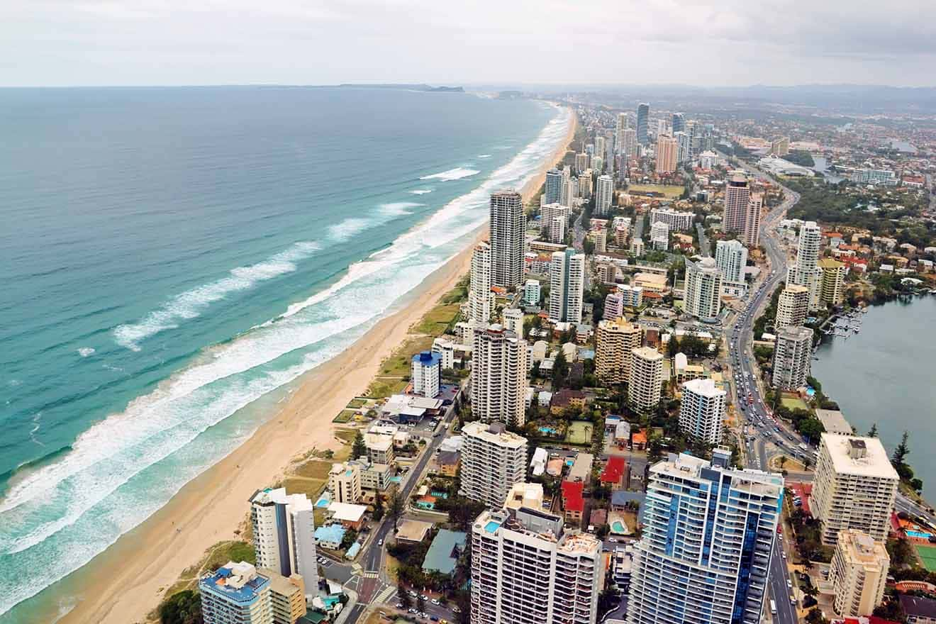 Aerial view of a coastal city with high-rise buildings along a sandy beach and waves rolling in from the ocean.