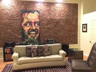 Contemporary living space with exposed brick wall featuring a vibrant painting of a smiling man