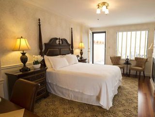 A traditional hotel room with a large bed, elegant wooden furniture, and two bedside lamps