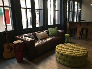 Cozy music lounge with a leather sofa, colorful ottoman, and musical instruments