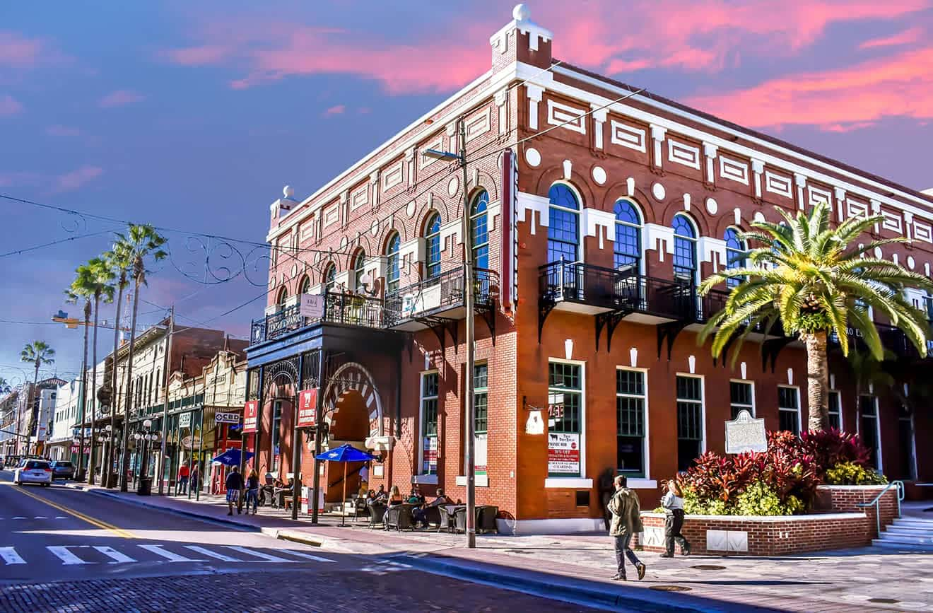 Street view of Ybor City in Tampa with historic buildings, palm trees, and clear blue sky.