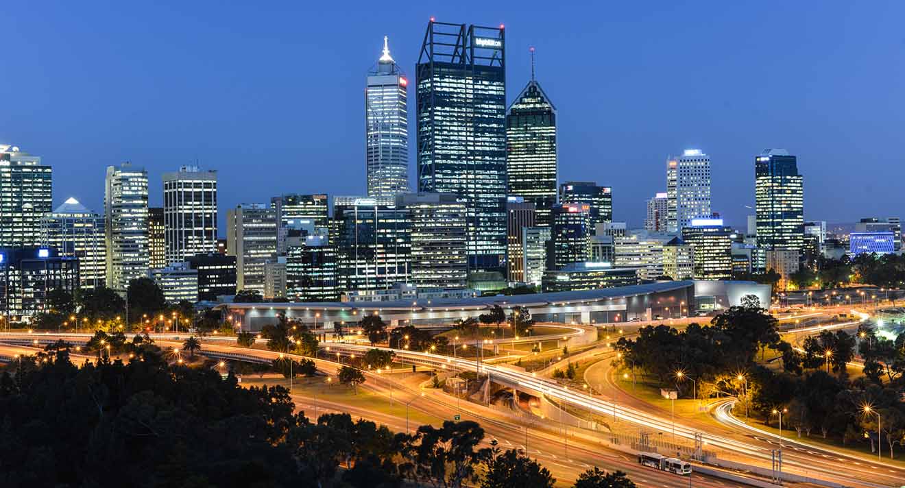 Nighttime cityscape with illuminated skyscrapers, busy highways, and a complex urban infrastructure