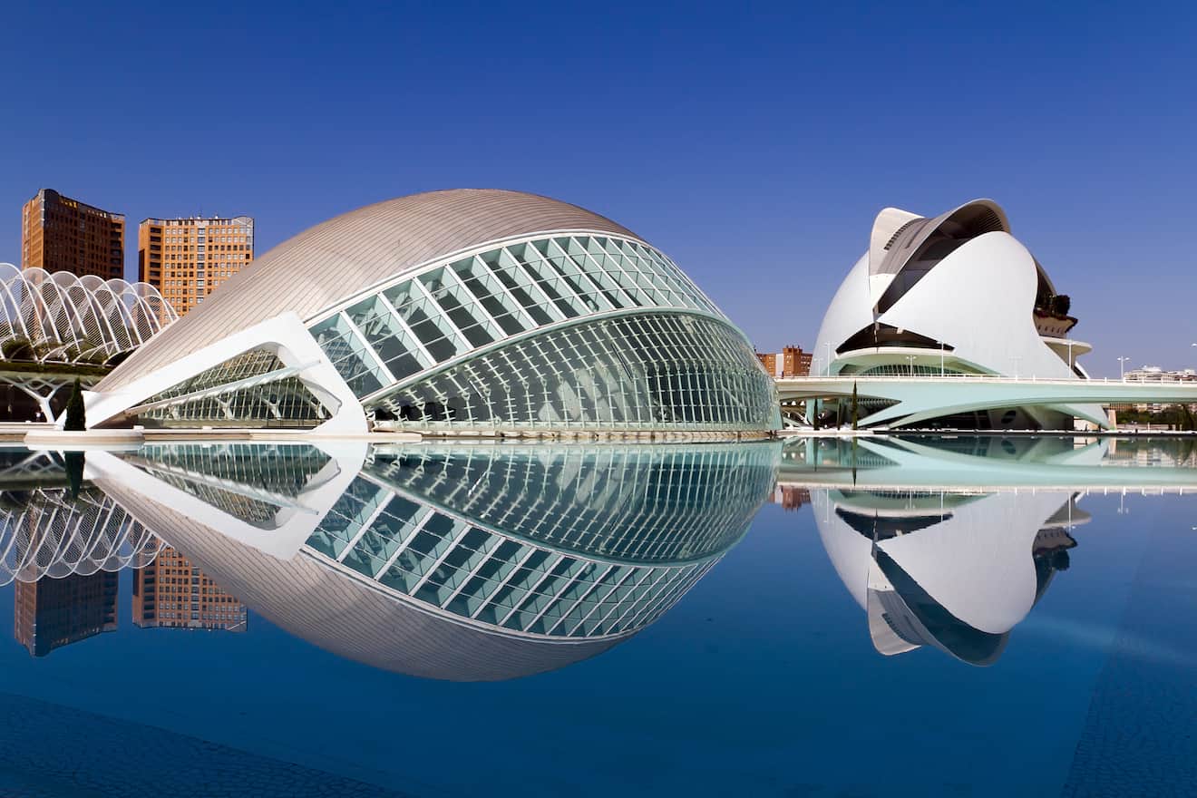 Image of the City of Arts and Sciences in Valencia, Spain, showing the distinctive modern architecture of the Hemisfèric and Palau de les Arts Reina Sofia on a clear day with reflections in the surrounding water