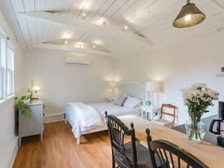 Bright and airy motel room with a comfortable bed, wooden dining set, white walls, and a beamed ceiling