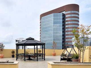 Rooftop terrace with a gazebo and seating area overlooking a modern high-rise building