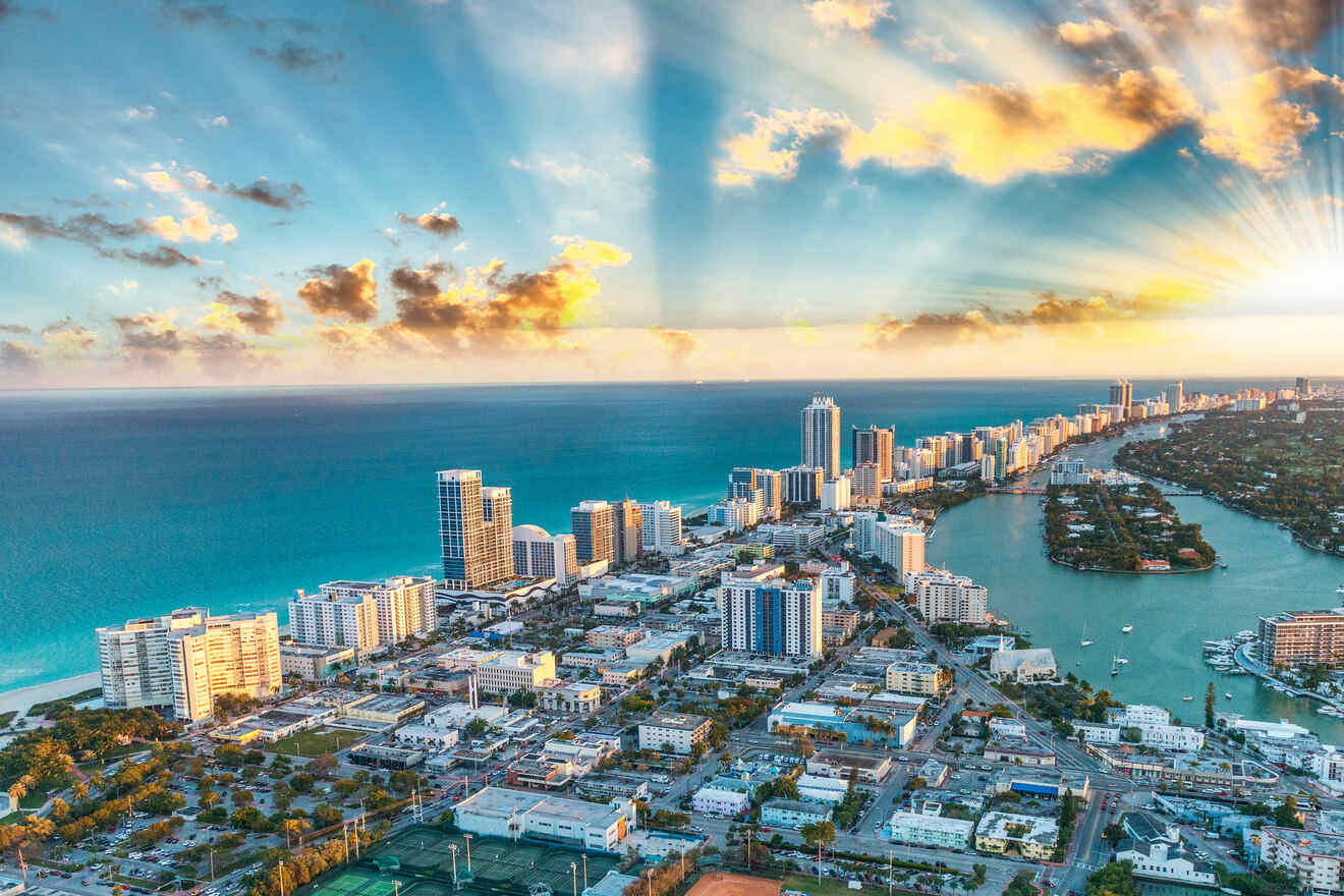 Aerial view of Miami skyline with skyscrapers and a vibrant sunset over the bay.